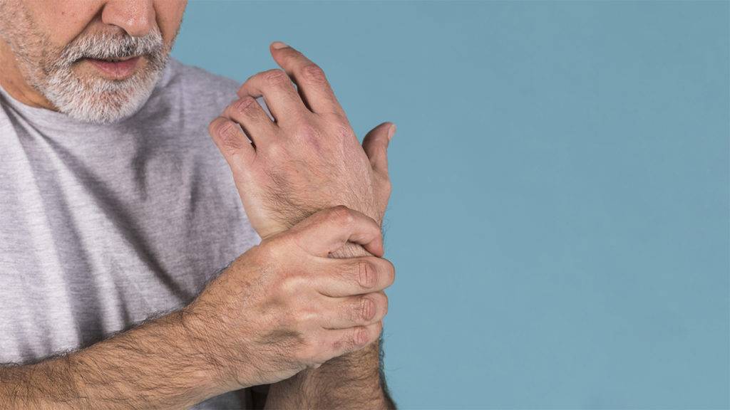Idoso segurando o pulso com dor nas juntas por causa da artrite.